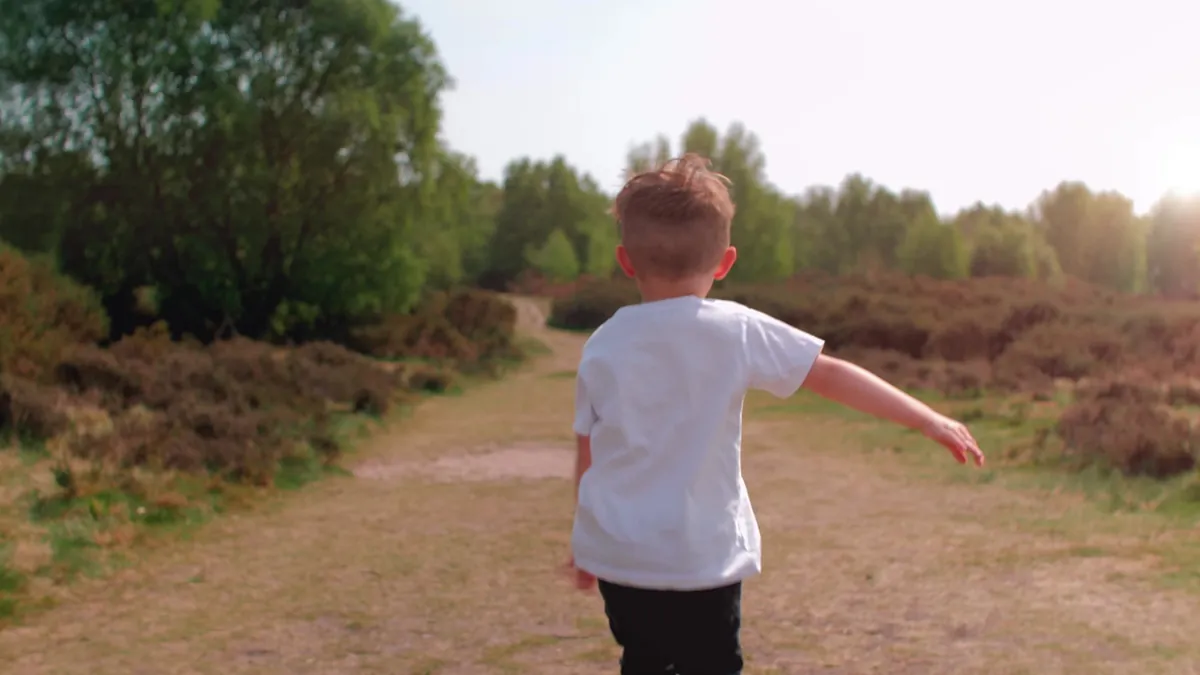 A young child running and laughing outdoors at an early learning centre, captured on location by Sprint Marketing.